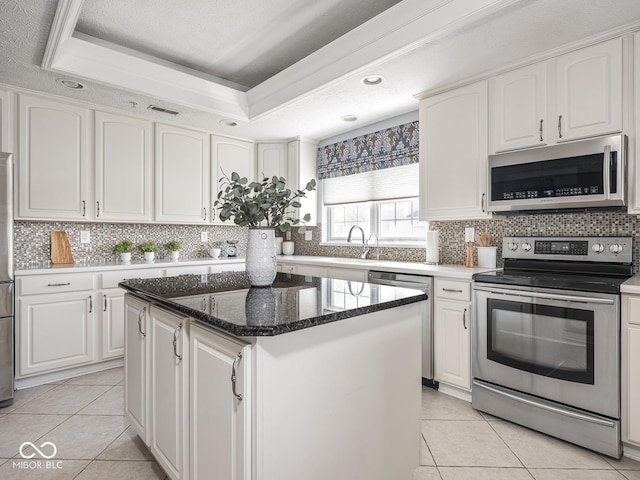6730 Spirit Lake Dr Unit 202, Indianapolis, IN 46220 - kitchen with stainless steel appliances, light tile patterned floors, white cabinetry, a kitchen island, and a raised ceiling