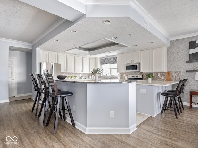 6730 Spirit Lake Dr Unit 202, Indianapolis, IN 46220 - kitchen featuring appliances with stainless steel finishes, a textured ceiling, a kitchen bar, crown molding, and white cabinetry