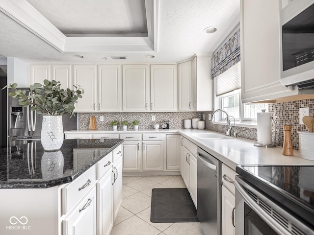 6730 Spirit Lake Dr Unit 202, Indianapolis, IN 46220 - kitchen with stainless steel appliances, white cabinetry, backsplash, a tray ceiling, and light tile patterned flooring