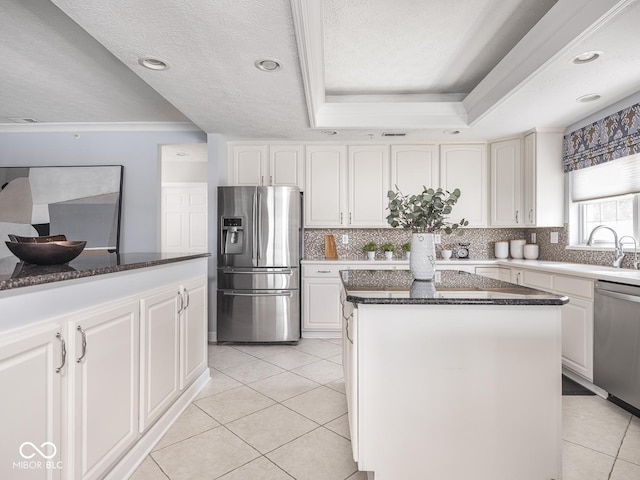 6730 Spirit Lake Dr Unit 202, Indianapolis, IN 46220 - kitchen featuring appliances with stainless steel finishes, a kitchen island, light tile patterned floors, a raised ceiling, and dark stone counters