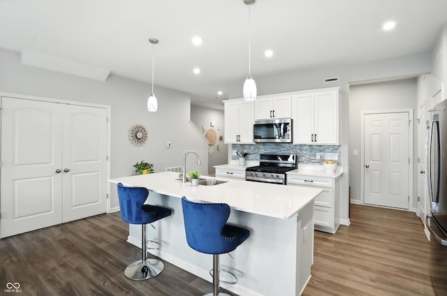 18750 Terra Vis Pl, Westfield, IN 46074 - kitchen featuring appliances with stainless steel finishes, decorative backsplash, dark wood-style flooring, a breakfast bar, and white cabinetry