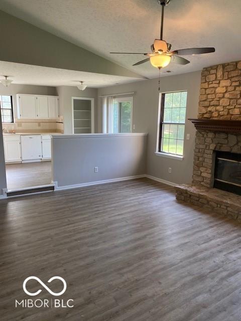 7313 Shanna Cir, Indianapolis, IN 46236 - unfurnished living room with ceiling fan, dark wood-style flooring, lofted ceiling, a fireplace, and a textured ceiling