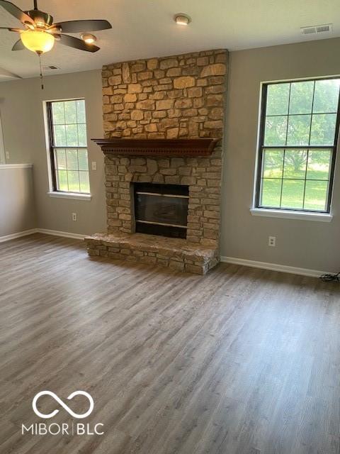 7313 Shanna Cir, Indianapolis, IN 46236 - unfurnished living room with a stone fireplace, wood finished floors, and ceiling fan