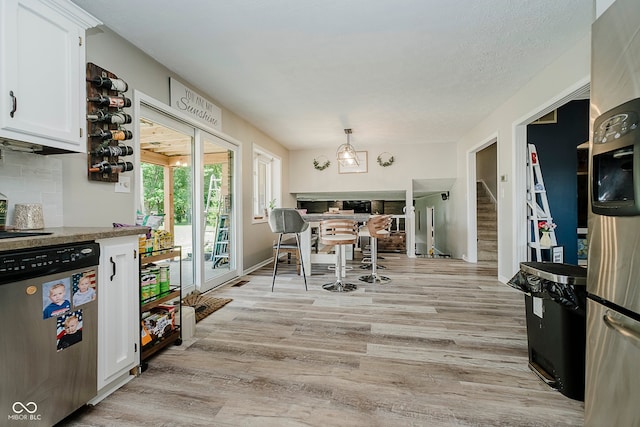 1616 Beech Cir, Plainfield, IN 46168 - kitchen with dishwasher, white cabinetry, light wood-style flooring, tasteful backsplash, and decorative light fixtures