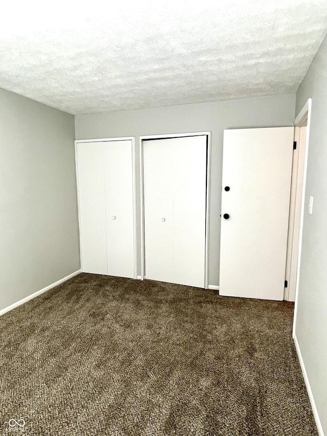 4933 Oakwood Trl, Indianapolis, IN 46268 - unfurnished bedroom featuring multiple closets, carpet flooring, and a textured ceiling