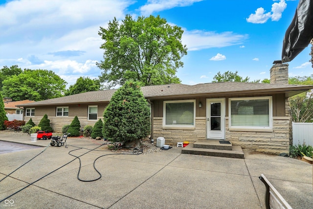 125 E Waterbury Rd, Indianapolis, IN 46227 - view of front of property with a chimney, stone siding, a patio area, and a shingled roof