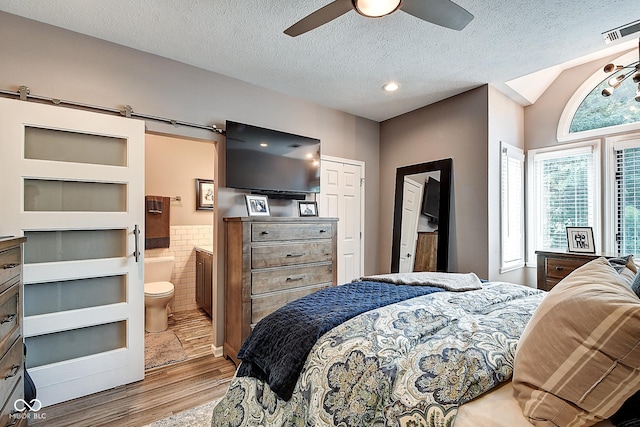 1551 N Park Ave, Indianapolis, IN 46202 - bedroom with wood finished floors, a textured ceiling, ensuite bath, tile walls, and a wainscoted wall