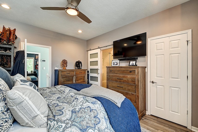 1551 N Park Ave, Indianapolis, IN 46202 - bedroom with wood finished floors, recessed lighting, a ceiling fan, a textured ceiling, and a barn door