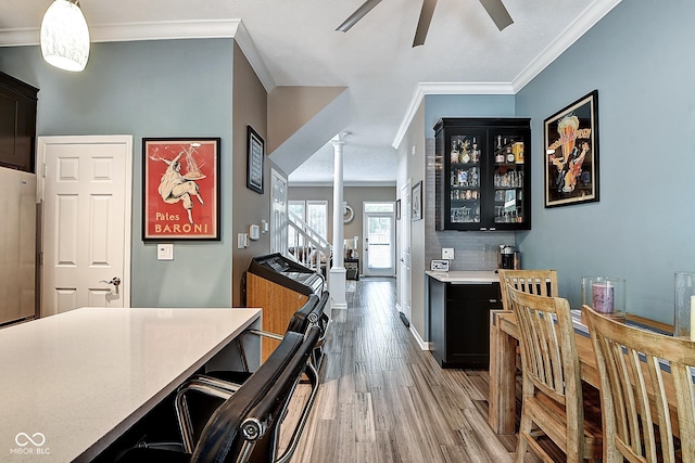 1551 N Park Ave, Indianapolis, IN 46202 - kitchen with ornate columns, dark cabinets, ceiling fan, light wood-style flooring, and light countertops