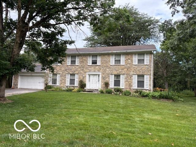10720 Lakeview Dr, Carmel, IN 46033 - colonial house featuring a front yard, a garage, concrete driveway, and stone siding