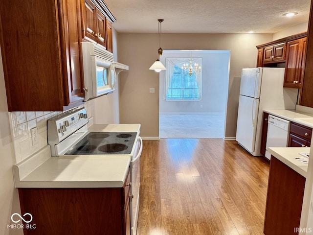 3400 W Riggin Rd, Muncie, IN 47304 - kitchen with white appliances, a chandelier, light wood-type flooring, pendant lighting, and light countertops