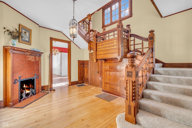 408 E Wabash Ave, Crawfordsville, IN 47933 - stairs featuring ornamental molding, hardwood / wood-style flooring, a fireplace, and a chandelier
