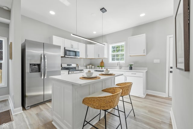 2012 N Dexter St, Indianapolis, IN 46202 - kitchen featuring appliances with stainless steel finishes, light countertops, light wood-type flooring, white cabinetry, and recessed lighting