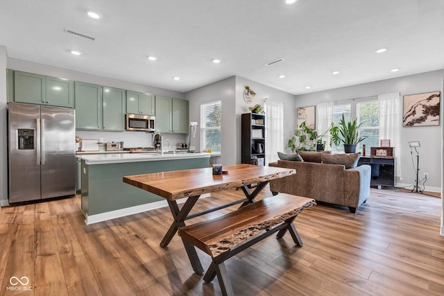 11480 Plough St, Noblesville, IN 46060 - kitchen with stainless steel appliances, green cabinets, light countertops, light wood-style floors, and recessed lighting