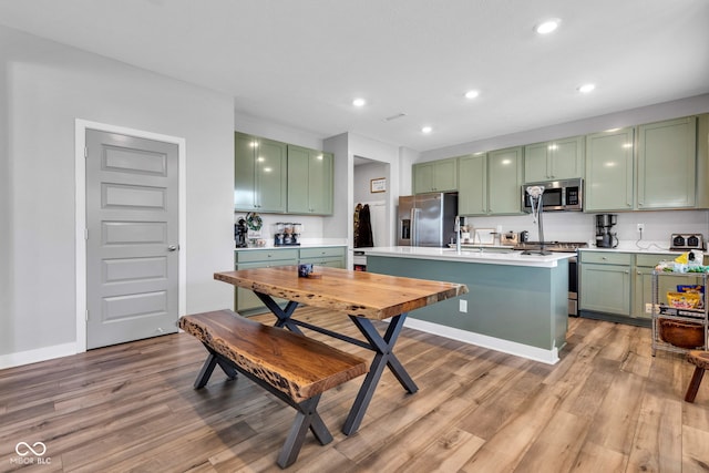 11480 Plough St, Noblesville, IN 46060 - kitchen with appliances with stainless steel finishes, green cabinetry, light countertops, light wood-type flooring, and recessed lighting