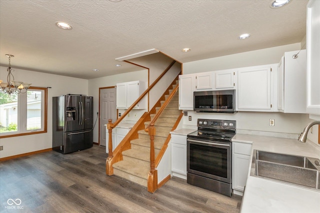 221 N Adams St, Brownsburg, IN 46112 - kitchen with appliances with stainless steel finishes, white cabinets, dark wood-style floors, light countertops, and a chandelier