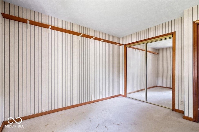 3628 Paddington Cir, Indianapolis, IN 46268 - unfurnished bedroom with a closet, a textured ceiling, carpet floors, and wallpapered walls
