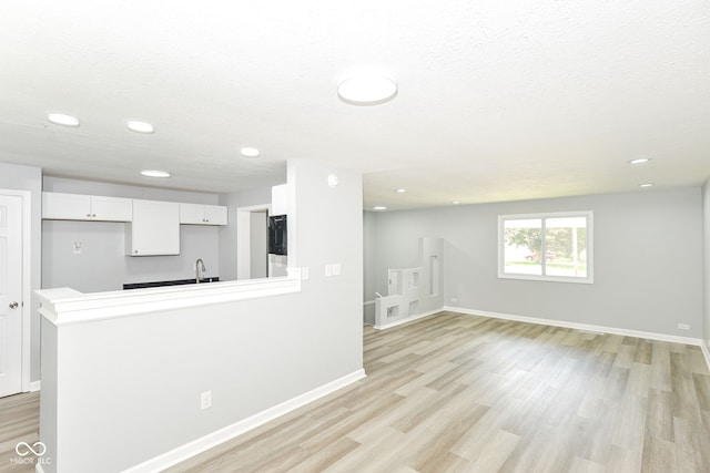 2521 Winfield Ave, Indianapolis, IN 46222 - kitchen with light wood-type flooring, white cabinetry, a peninsula, recessed lighting, and light countertops