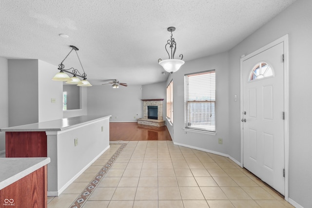 12443 Rose Haven Dr, Indianapolis, IN 46235 - kitchen with ceiling fan, a stone fireplace, decorative light fixtures, light countertops, and a textured ceiling