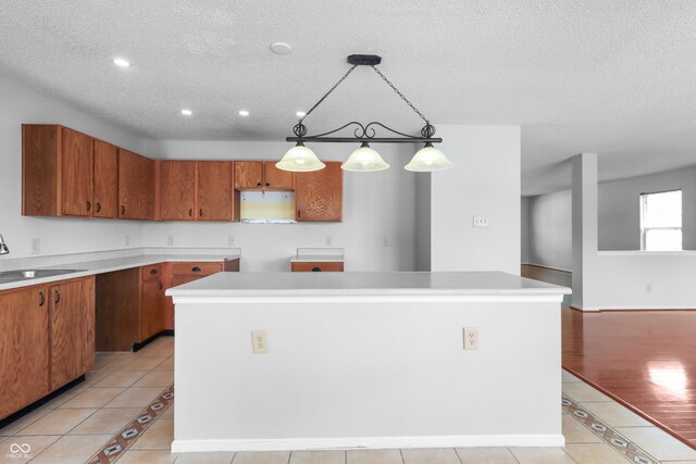 12443 Rose Haven Dr, Indianapolis, IN 46235 - kitchen featuring a kitchen island, a textured ceiling, brown cabinets, light tile patterned flooring, and decorative light fixtures