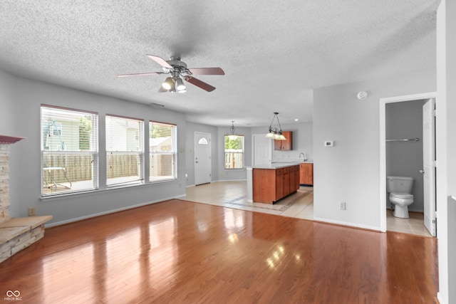 12443 Rose Haven Dr, Indianapolis, IN 46235 - unfurnished living room featuring a textured ceiling, ceiling fan, light wood finished floors, and a stone fireplace