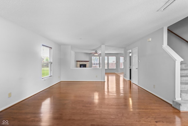12443 Rose Haven Dr, Indianapolis, IN 46235 - unfurnished living room with wood finished floors, ceiling fan, a textured ceiling, stairway, and a fireplace