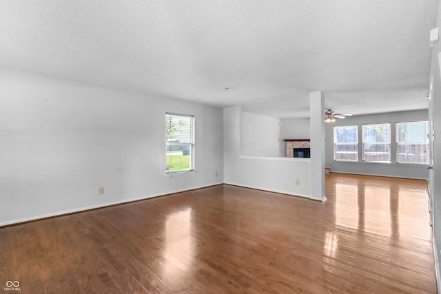 12443 Rose Haven Dr, Indianapolis, IN 46235 - unfurnished living room featuring a glass covered fireplace, wood finished floors, a ceiling fan, and a textured ceiling