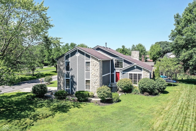 826 Royal Saint George Dr, Greenwood, IN 46143 - mid-century home featuring stone siding, a chimney, a front yard, and a trampoline