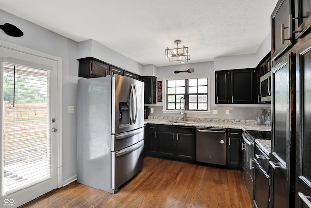 826 Royal Saint George Dr, Greenwood, IN 46143 - kitchen with stainless steel appliances, dark wood finished floors, light stone countertops, dark cabinetry, and a chandelier