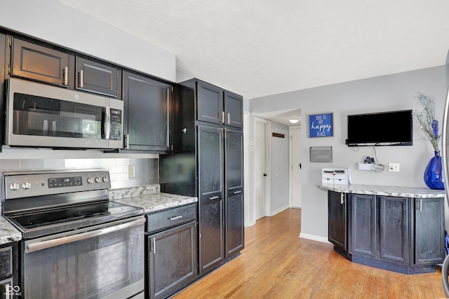 826 Royal Saint George Dr, Greenwood, IN 46143 - kitchen with stainless steel appliances, light wood-style flooring, tasteful backsplash, and light stone counters