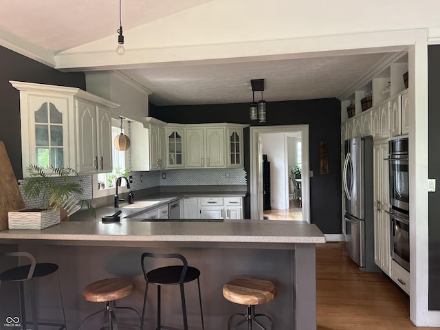 2131 Union St, Lafayette, IN 47904 - kitchen featuring stainless steel appliances, a peninsula, a breakfast bar, wood finished floors, and vaulted ceiling