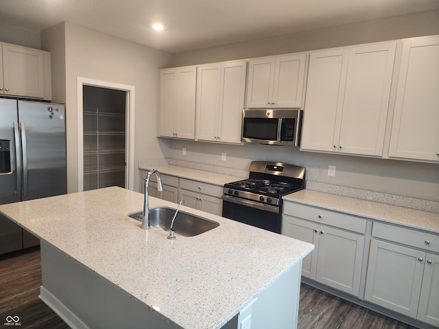 2431 S Carlota Dr, New Palestine, IN 46163 - kitchen featuring stainless steel appliances, recessed lighting, dark wood-style floors, light stone counters, and a kitchen island with sink