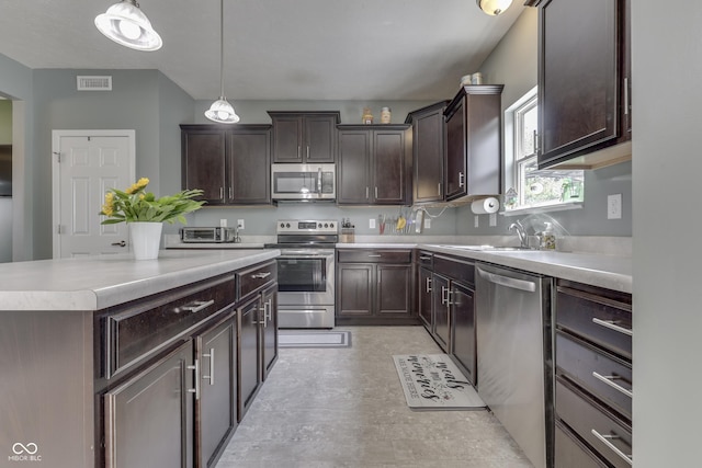 12291 Falling Leaves Trl, Indianapolis, IN 46229 - kitchen featuring appliances with stainless steel finishes, dark brown cabinetry, light countertops, a center island, and pendant lighting