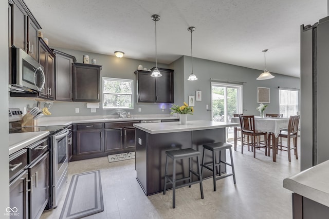 12291 Falling Leaves Trl, Indianapolis, IN 46229 - kitchen with appliances with stainless steel finishes, dark brown cabinetry, light countertops, a kitchen bar, and a textured ceiling