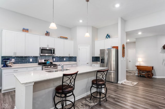 2584 Lanai Ln, Greenwood, IN 46143 - kitchen featuring appliances with stainless steel finishes, an island with sink, decorative backsplash, white cabinetry, and a breakfast bar area
