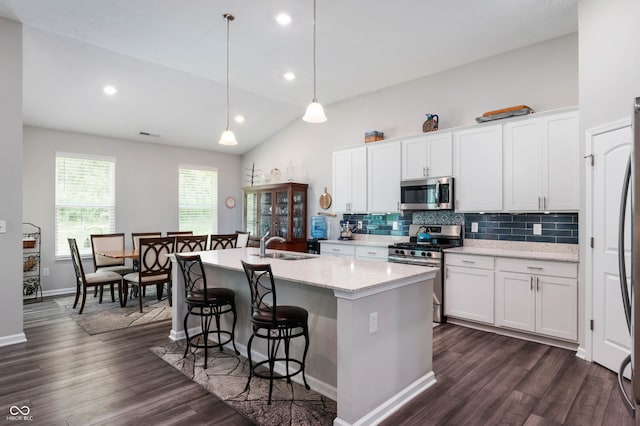 2584 Lanai Ln, Greenwood, IN 46143 - kitchen featuring appliances with stainless steel finishes, vaulted ceiling, decorative backsplash, dark wood-style floors, and a breakfast bar area
