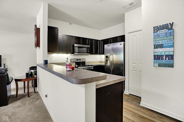 12075 Scoria Dr Unit 500, Fishers, IN 46038 - kitchen with appliances with stainless steel finishes, dark cabinets, a peninsula, and wood finished floors