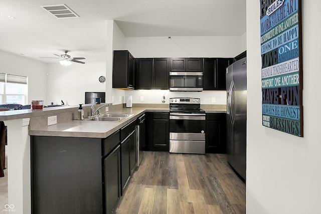 12075 Scoria Dr Unit 500, Fishers, IN 46038 - kitchen with appliances with stainless steel finishes, dark wood finished floors, a ceiling fan, dark cabinetry, and a peninsula