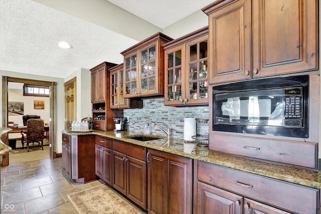 523 S 700 E, Whitestown, IN 46075 - kitchen featuring black microwave, a textured ceiling, light stone counters, backsplash, and glass insert cabinets