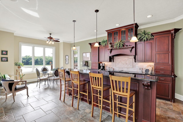 523 S 700 E, Whitestown, IN 46075 - kitchen featuring reddish brown cabinets, stone tile floors, tasteful backsplash, ceiling fan, and a kitchen island