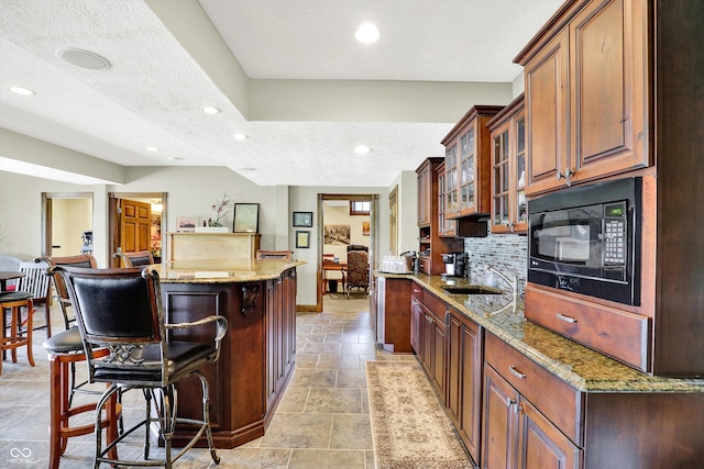 523 S 700 E, Whitestown, IN 46075 - kitchen featuring black microwave, a kitchen breakfast bar, backsplash, a center island, and glass insert cabinets