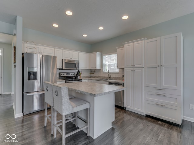 8330 Whitaker Valley Blvd, Indianapolis, IN 46237 - kitchen with appliances with stainless steel finishes, a kitchen island, white cabinetry, a breakfast bar area, and dark wood finished floors