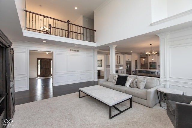 10334 Strongbow Rd, Fishers, IN 46040 - living room with a decorative wall, a chandelier, a high ceiling, ornate columns, and wood finished floors