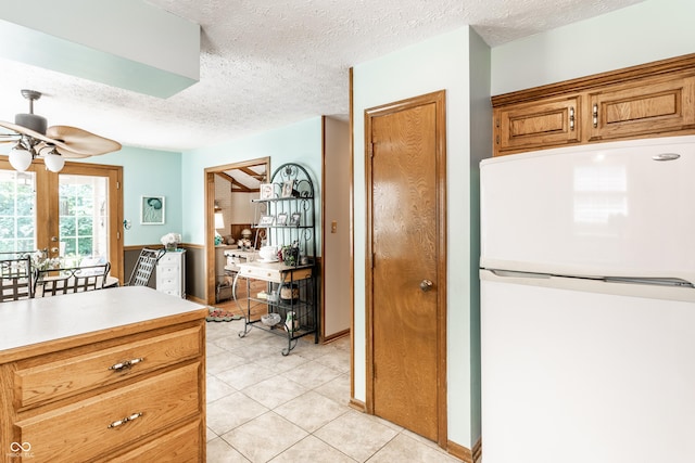 5123 Marble Ct, Indianapolis, IN 46237 - kitchen with freestanding refrigerator, a textured ceiling, a ceiling fan, light countertops, and brown cabinetry
