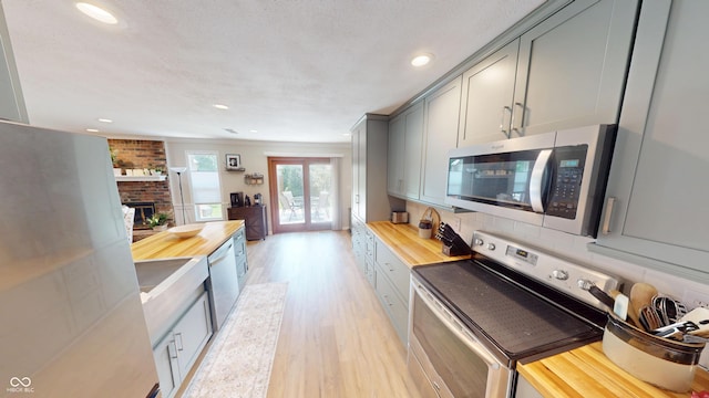 1623 Beech Cir, Plainfield, IN 46168 - kitchen featuring stainless steel appliances, gray cabinets, light wood finished floors, wooden counters, and a brick fireplace