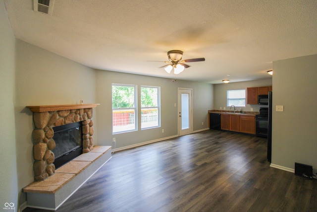 10610 Pavilion Dr, Indianapolis, IN 46259 - unfurnished living room with dark wood-type flooring, ceiling fan, a stone fireplace, and a textured ceiling