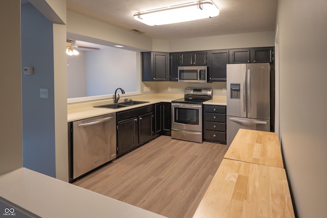 7151 Sea Pine Dr, Indianapolis, IN 46250 - kitchen featuring appliances with stainless steel finishes, light wood-type flooring, dark cabinetry, a ceiling fan, and a textured ceiling