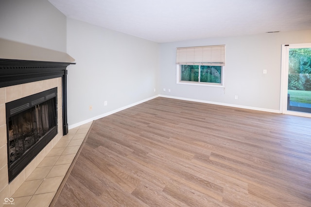 7151 Sea Pine Dr, Indianapolis, IN 46250 - unfurnished living room featuring a tiled fireplace and light wood-type flooring