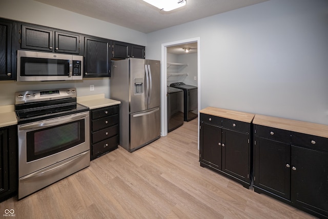 7151 Sea Pine Dr, Indianapolis, IN 46250 - kitchen featuring appliances with stainless steel finishes, dark cabinetry, washer and dryer, light wood-type flooring, and a textured ceiling