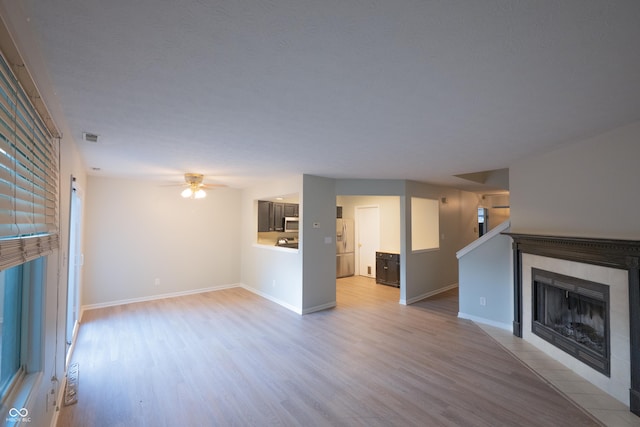 7151 Sea Pine Dr, Indianapolis, IN 46250 - unfurnished living room with wood finished floors, a tiled fireplace, and ceiling fan